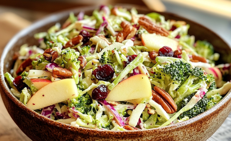 A vibrant bowl of Apple Broccoli Slaw with Cranberry Pecan Dressing, showcasing fresh broccoli, juicy apple slices, tart cranberries, and crunchy pecans, styled beautifully on a rustic table.